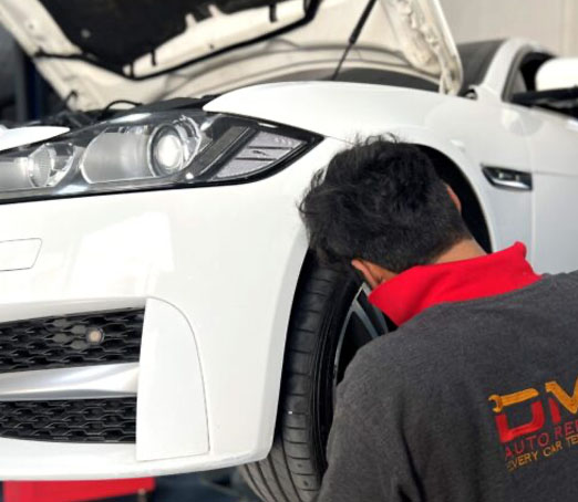 DME Auto Technician Servicing Jaguar Car in Workshop